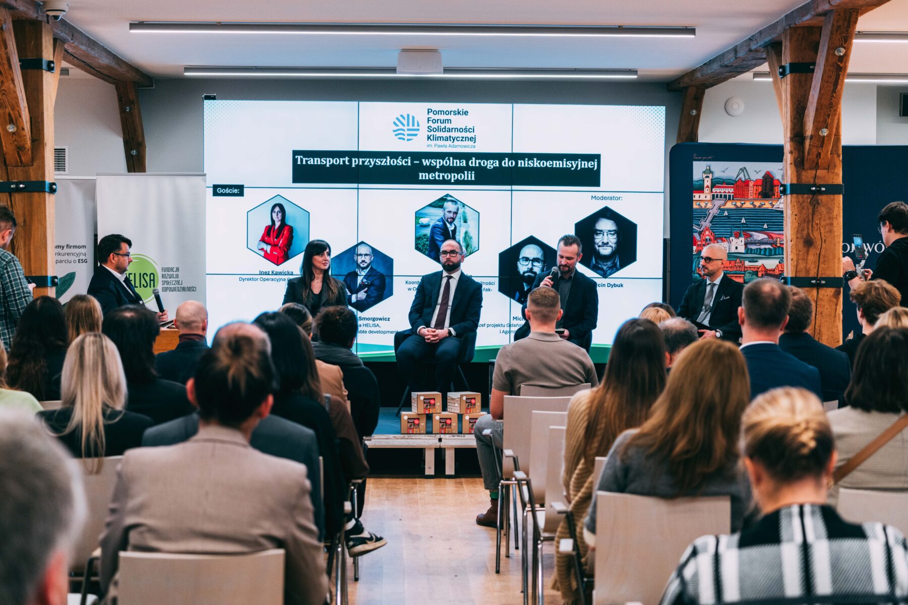 Panel dyskusyjny na Pomorskim Forum Solidarności Klimatycznej. Prelegenci na scenie, ekran z tematem, widownia.